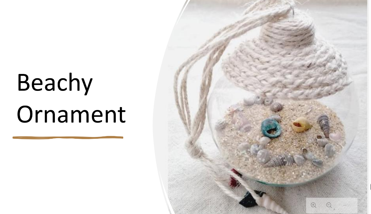 Image of clear, circular ornament, containing sand, shells, small stones and embellished with braided nautical twine.